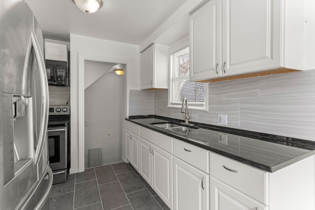 kitchen with backsplash, sink, dark tile patterned floors, appliances with stainless steel finishes, and white cabinets