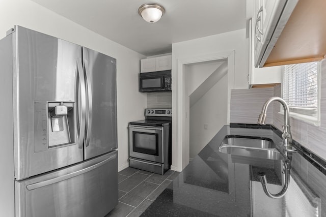 kitchen featuring backsplash, sink, dark tile patterned floors, appliances with stainless steel finishes, and white cabinets