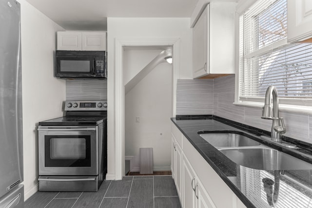 kitchen with tasteful backsplash, white cabinets, appliances with stainless steel finishes, and sink