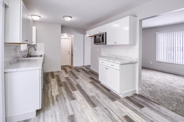 kitchen featuring carpet, backsplash, white cabinets, and sink