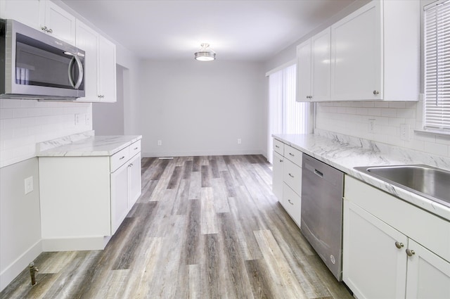 kitchen with stainless steel appliances, light hardwood / wood-style flooring, white cabinetry, and light stone countertops