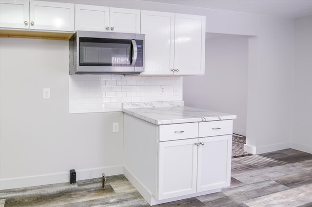 kitchen featuring light hardwood / wood-style floors, light stone countertops, backsplash, and white cabinets