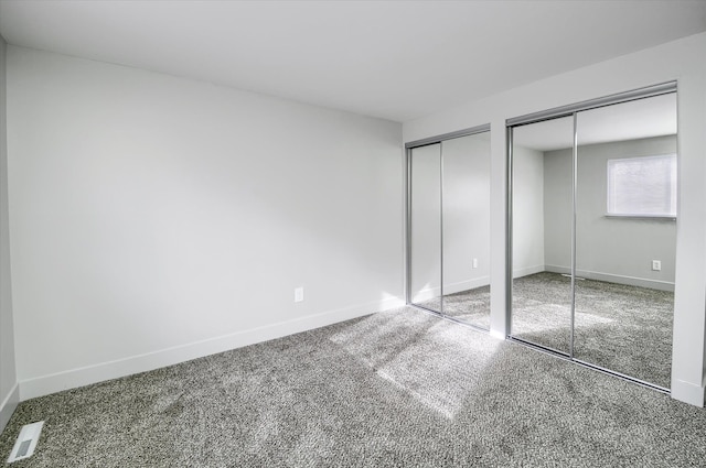 unfurnished bedroom featuring carpet floors and multiple closets