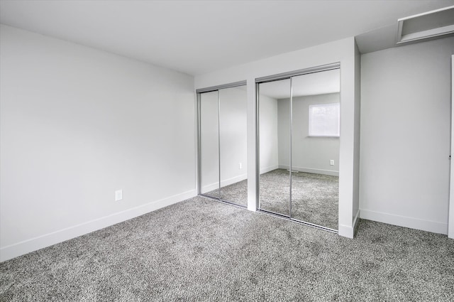 unfurnished bedroom featuring carpet and multiple closets