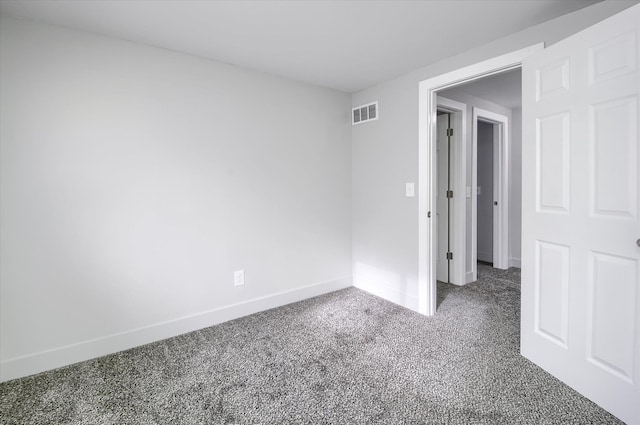 spare room featuring dark colored carpet