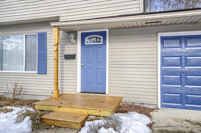 snow covered property entrance featuring a garage