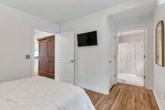 bedroom with connected bathroom and light wood-type flooring