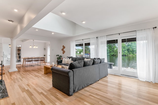 living room with a healthy amount of sunlight, decorative columns, and light wood-type flooring