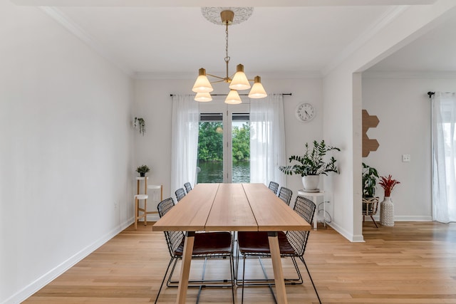 dining room with an inviting chandelier, crown molding, and light wood-type flooring