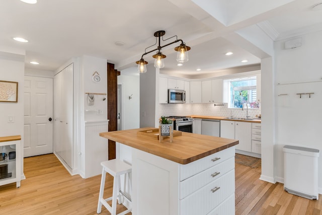 kitchen featuring sink, white cabinetry, wooden counters, decorative light fixtures, and stainless steel appliances