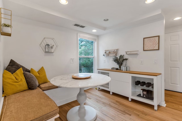 dining space with a tray ceiling, light hardwood / wood-style flooring, beverage cooler, and breakfast area