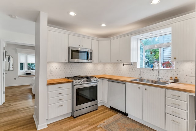 kitchen featuring appliances with stainless steel finishes, wood counters, white cabinetry, sink, and light hardwood / wood-style flooring