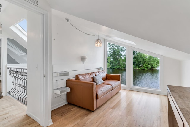 living room featuring vaulted ceiling with skylight and light wood-type flooring