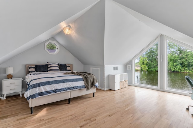 bedroom featuring multiple windows, vaulted ceiling, access to exterior, and light hardwood / wood-style floors