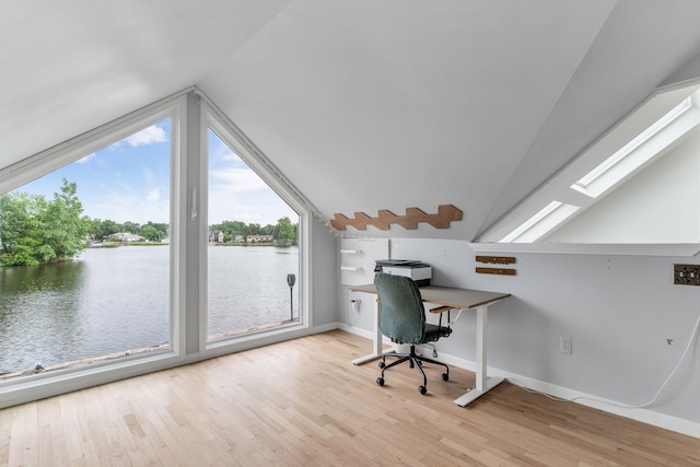 unfurnished office featuring a water view, lofted ceiling with skylight, light hardwood / wood-style floors, and a wealth of natural light