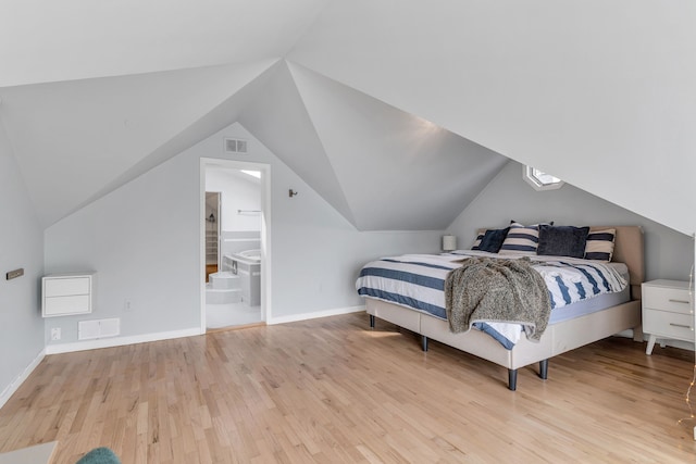 bedroom featuring ensuite bathroom, vaulted ceiling, and light hardwood / wood-style flooring