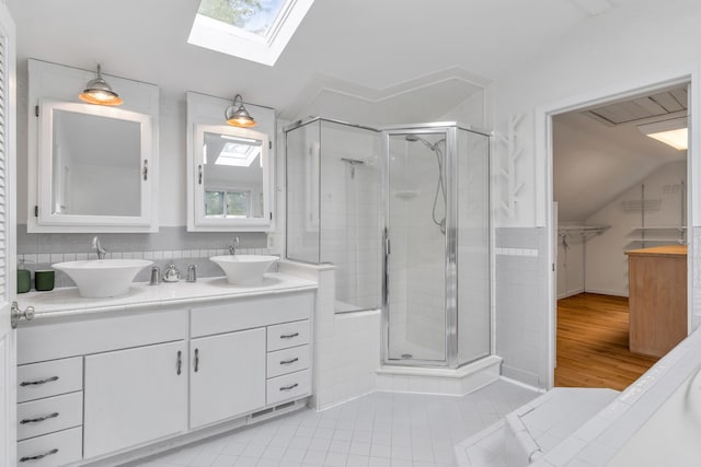 bathroom featuring tile patterned flooring, vanity, vaulted ceiling with skylight, and a shower with shower door