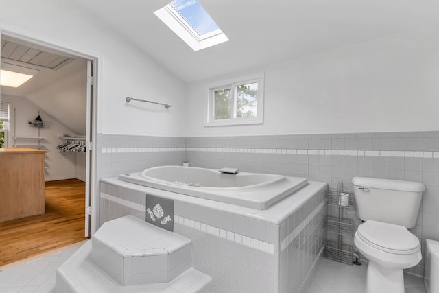 bathroom featuring tile patterned flooring, vaulted ceiling, tile walls, and toilet