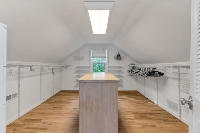 walk in closet featuring vaulted ceiling and light hardwood / wood-style flooring