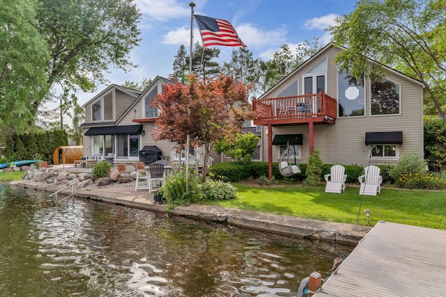 rear view of house with a water view, a yard, and a patio