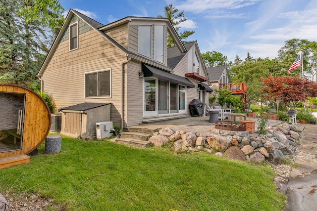 rear view of property with an outdoor fire pit, a yard, a shed, and a patio area