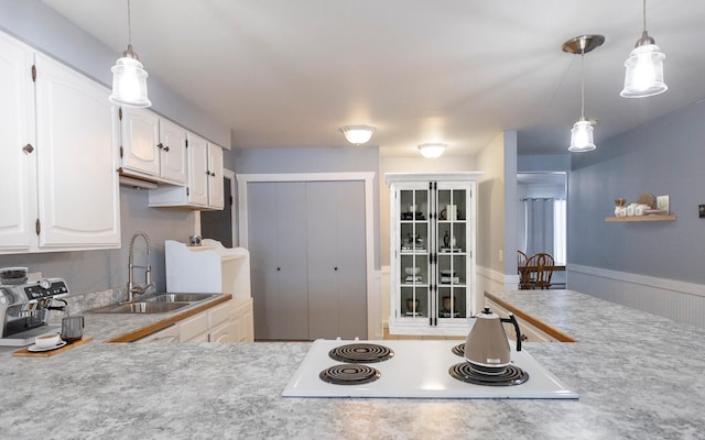 kitchen featuring sink, pendant lighting, white cabinetry, and white electric cooktop