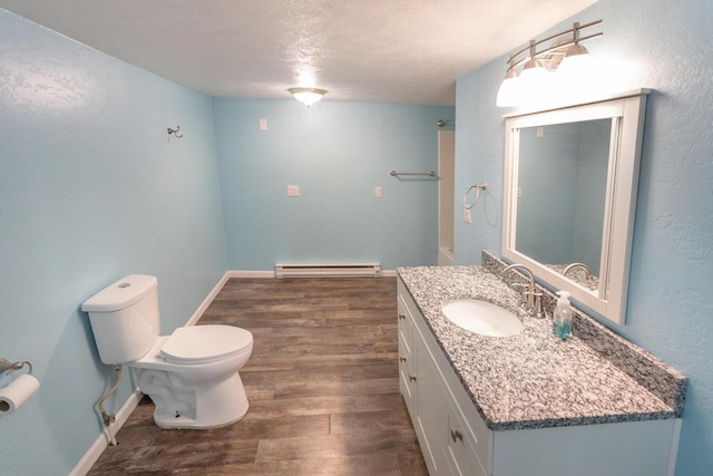 bathroom featuring hardwood / wood-style floors, a textured ceiling, a baseboard heating unit, vanity, and toilet