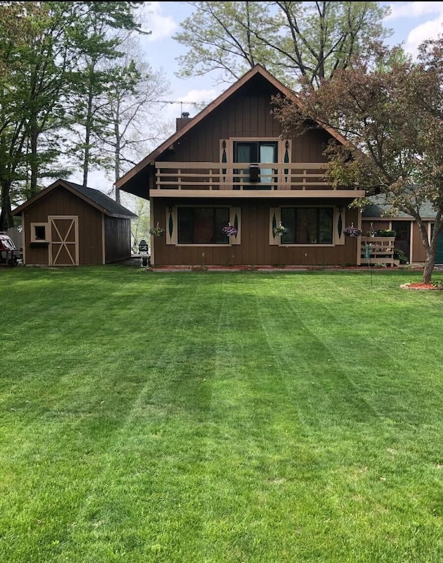 rear view of property featuring a balcony, a shed, and a lawn