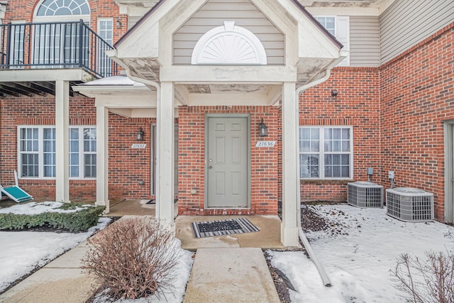 snow covered property entrance featuring central AC unit