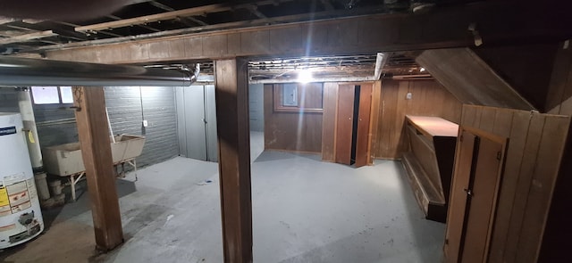 basement with electric panel, gas water heater, and wooden walls