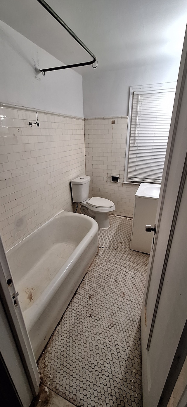 bathroom with toilet, tile patterned flooring, and tile walls