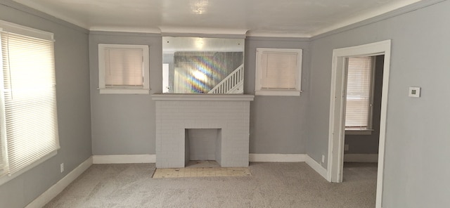 carpeted empty room with a brick fireplace and crown molding