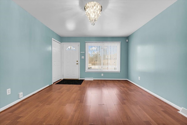 foyer with hardwood / wood-style floors and a chandelier