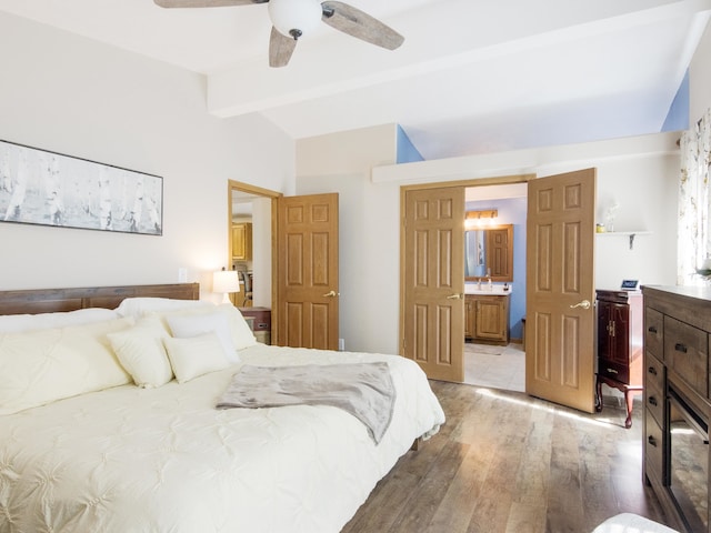 bedroom featuring ensuite bath, vaulted ceiling with beams, light hardwood / wood-style floors, sink, and ceiling fan