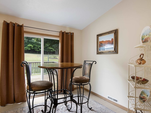 dining area with light tile patterned floors and lofted ceiling