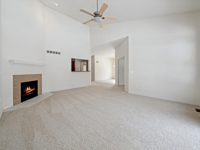 unfurnished living room with high vaulted ceiling, visible vents, a high end fireplace, ceiling fan, and carpet floors