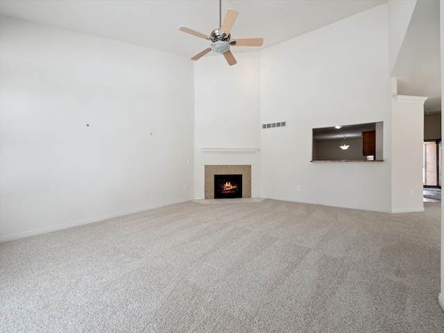 unfurnished living room with carpet, a fireplace with flush hearth, a high ceiling, visible vents, and a ceiling fan