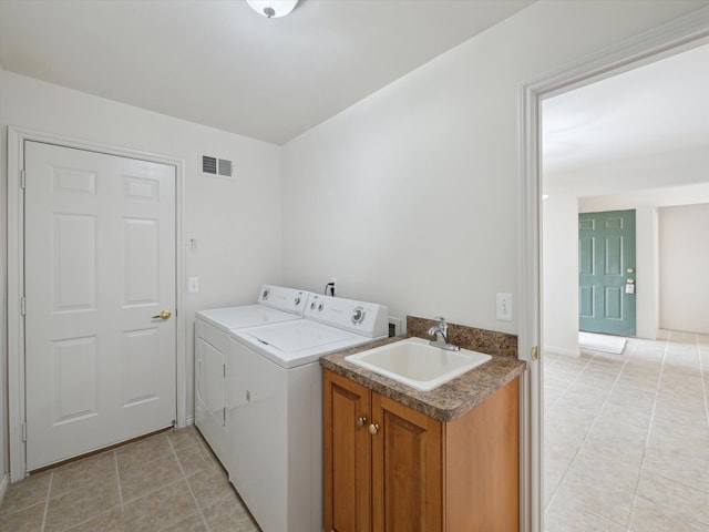 washroom with visible vents, a sink, washer and clothes dryer, cabinet space, and light tile patterned floors