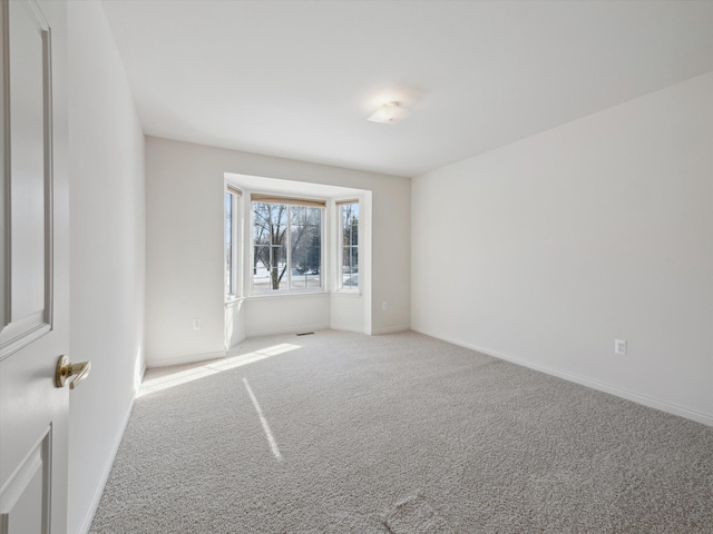 spare room featuring baseboards, carpet floors, and visible vents