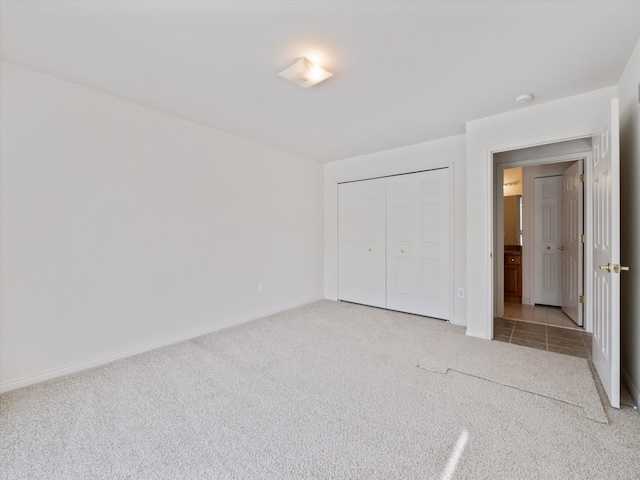 unfurnished bedroom with light carpet, baseboards, and a closet