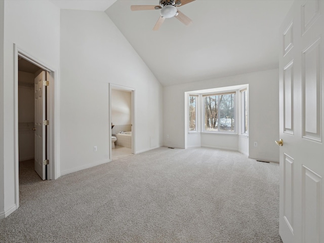 unfurnished bedroom with high vaulted ceiling, a walk in closet, carpet, and baseboards