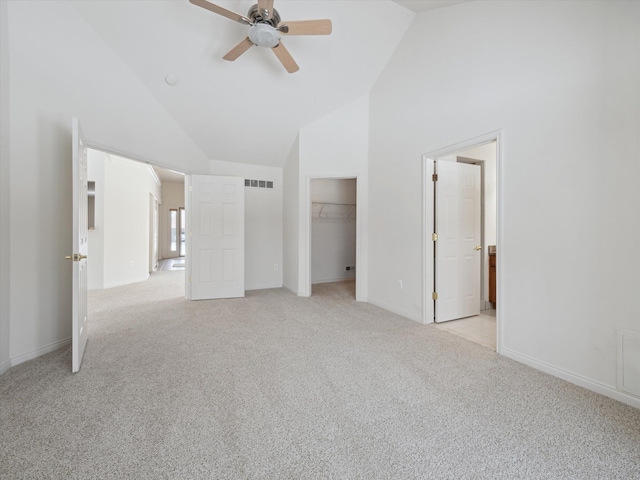unfurnished bedroom featuring light carpet, high vaulted ceiling, baseboards, and visible vents