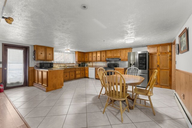 42891 Bemis Rd, Sumpter, MI 48111 - tiled dining space featuring baseboard heating, sink, wood walls, and a textured ceiling