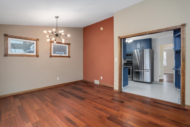 spare room featuring dark wood-type flooring, lofted ceiling, and a notable chandelier