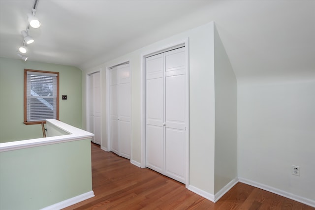 hall featuring rail lighting and wood-type flooring