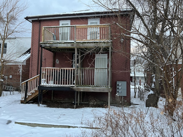 snow covered house featuring a balcony