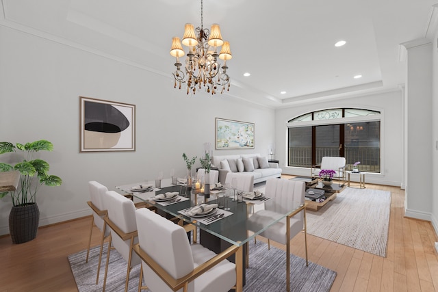 dining area featuring light hardwood / wood-style floors, a raised ceiling, and a chandelier