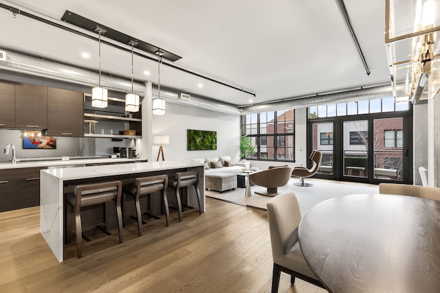 kitchen featuring a center island, light hardwood / wood-style floors, hanging light fixtures, a breakfast bar, and dark brown cabinets