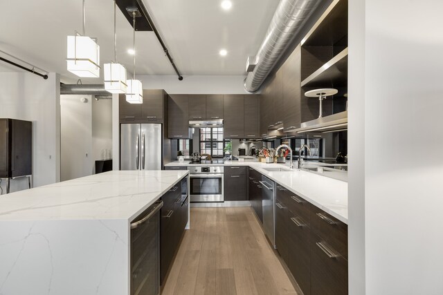 kitchen featuring beverage cooler, appliances with stainless steel finishes, a center island, decorative light fixtures, and hardwood / wood-style flooring