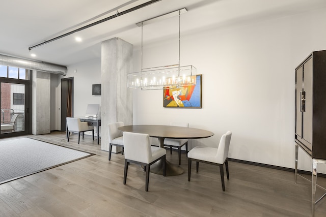 dining area with hardwood / wood-style flooring, track lighting, and an inviting chandelier